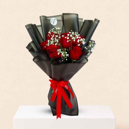 Fresh 10 red roses hand bouquet wrapped in elegant luxury black floral paper for romantic occasions with same-day flower delivery in Doha and across Qatar.